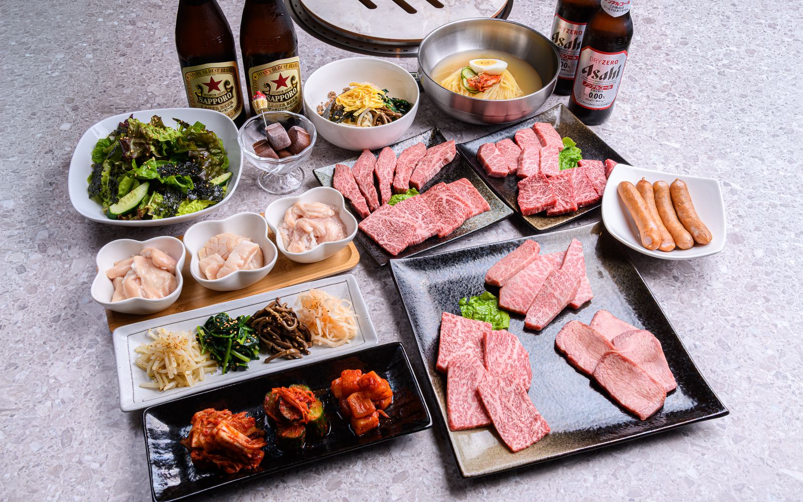 焼肉 伽耶のテーブルいっぱいに並んだ焼肉・冷麺・キムチ・ナムルの盛り合わせ